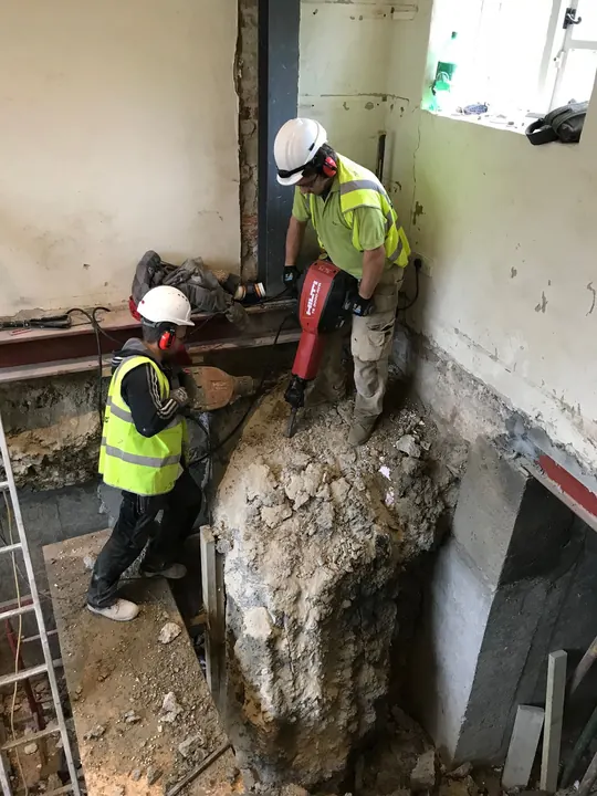 Two operatives using breakers beside a steel beam to open up the structure of a house