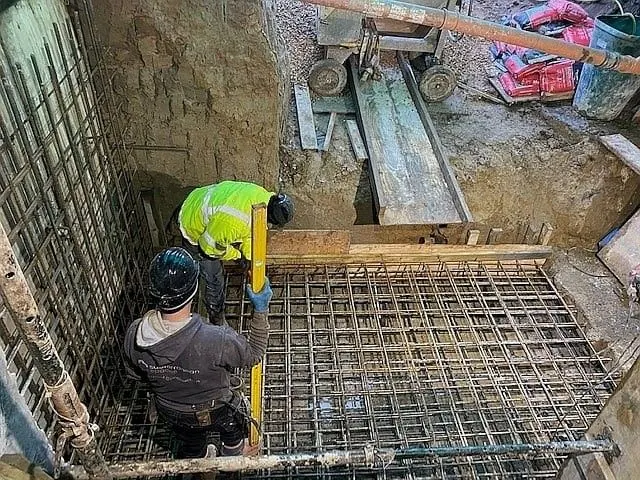 Operatives fixing steel reinforcement mesh for a basement slab at the bottom of a deep excavation